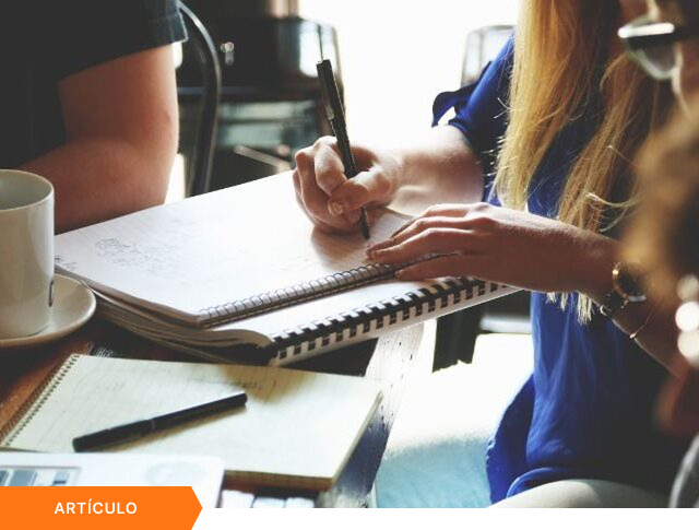 Primer plano de una profesional tomando notas a mano en un cuaderno durante una sesión de colaboración en equipo sobre gestión de proyectos e innovación empresarial, presentado como cabecera visual para un artículo.