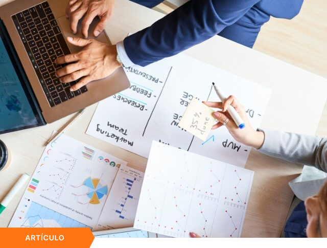 Vista superior de un equipo colaborando en el análisis de métricas y el seguimiento de avances para la gestión de proyectos e innovación empresarial, enmarcado como cabecera de artículo sobre portafolio estratégico.