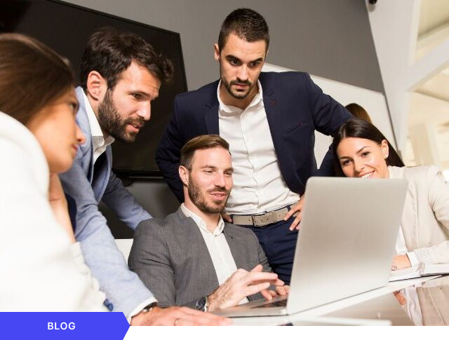 Equipo de profesionales reunidos alrededor de una laptop, colaborando en la revisión digital de avances para la gestión ágil de proyectos y la innovación empresarial, presentado como imagen principal para una entrada de blog.