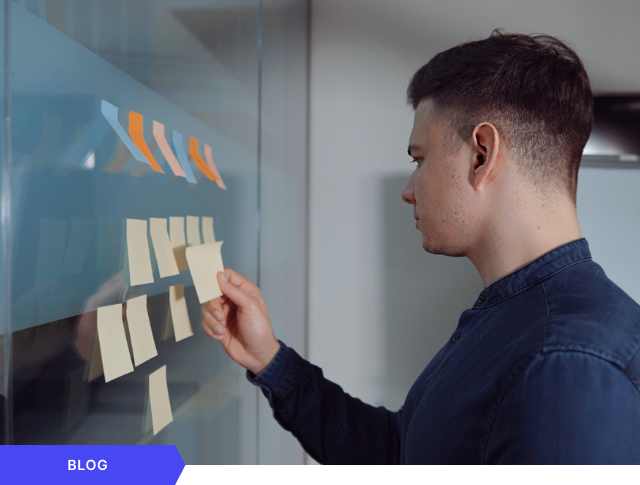 Profesional organizando ideas y tareas con notas adhesivas en una pared de cristal para la planificación y gestión ágil de proyectos de innovación empresarial, enmarcado como imagen principal para una entrada de blog.