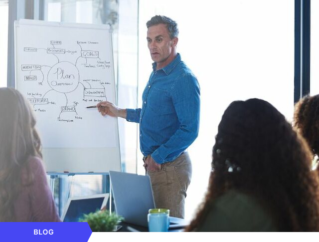Profesional liderando una reunión interactiva y presentando un plan estratégico mediante un mapa mental en un rotafolio, diseñado como imagen de cabecera para una entrada de blog sobre gestión de proyectos.