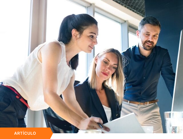 Imagen de portada para artículo mostrando a tres profesionales analizando datos en un monitor de escritorio en una oficina luminosa, con una etiqueta naranja de ARTÍCULO en la esquina inferior izquierda.