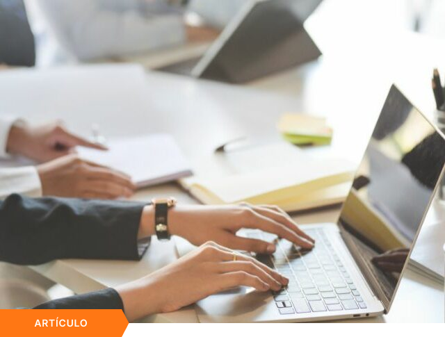 Imagen de portada para artículo mostrando el primer plano de una profesional trabajando en su laptop en una oficina, con una etiqueta naranja de ARTÍCULO en la esquina inferior izquierda.