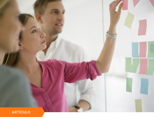 Imagen de portada para artículo que muestra a tres profesionales organizando notas adhesivas en una pared de cristal, con una etiqueta naranja de ARTÍCULO en la esquina inferior izquierda.