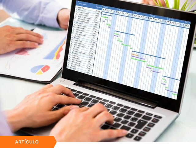 Imagen de portada para artículo mostrando a un equipo colaborando con una laptop que visualiza un diagrama de Gantt y reportes impresos, con una etiqueta naranja de ARTÍCULO en la esquina inferior izquierda.