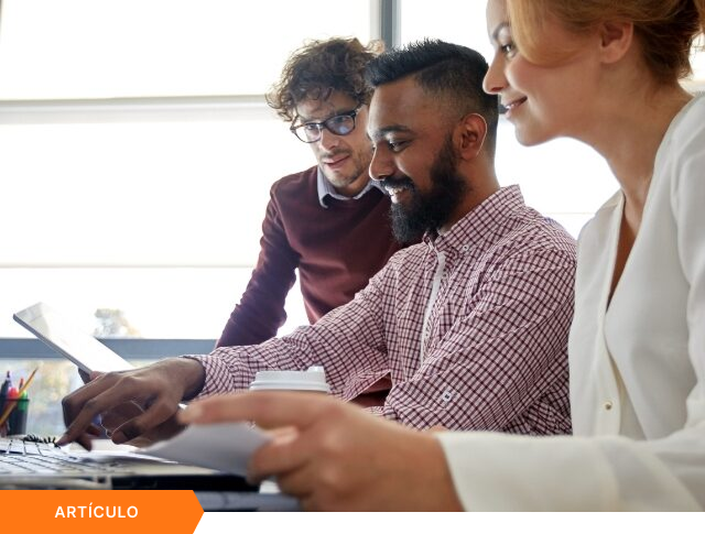 Imagen de portada para artículo que muestra a tres profesionales diversos colaborando activamente frente a una laptop y una tablet, con una etiqueta naranja de ARTÍCULO en la esquina inferior izquierda.