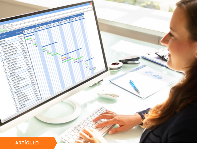 Imagen de portada para artículo mostrando a una profesional analizando un diagrama de Gantt en un monitor de escritorio, con una etiqueta naranja de ARTÍCULO en la esquina inferior izquierda.