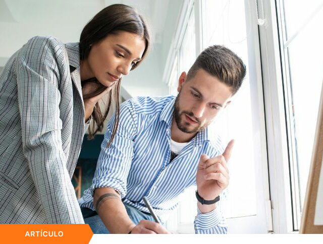 Imagen de portada para artículo mostrando a dos consultores analizando gráficos de rendimiento en un tablero físico, con una etiqueta naranja de ARTÍCULO en la esquina inferior izquierda.