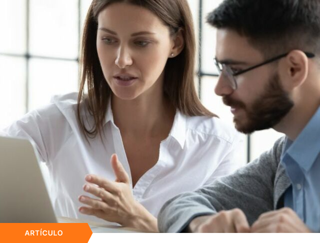Imagen de portada para artículo que muestra a una profesional gesticulando mientras lidera una explicación enfocada frente a una laptop junto a un colega, con una etiqueta naranja de ARTÍCULO en la esquina inferior izquierda.