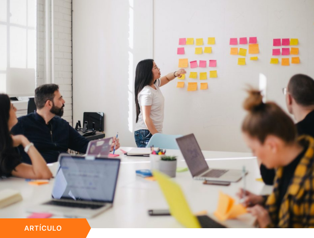 Portada de artículo que muestra a un equipo en una sesión de brainstorming con notas adhesivas en la pared, con etiqueta naranja de ARTÍCULO en la esquina inferior izquierda.