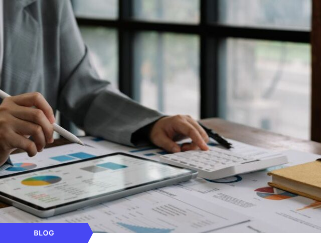 Primer plano de las manos de un profesional utilizando un lápiz óptico sobre una tablet con gráficos de rendimiento y trabajando con una calculadora, diseñada como imagen de portada para un artículo de blog sobre análisis financiero, rentabilidad y cálculo del ROI en la gestión de proyectos de innovación.