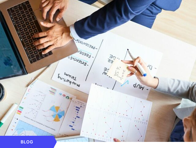 Vista aérea de un equipo de trabajo analizando gráficos de rendimiento y KPIs en una oficina, con una nota adhesiva que indica un 35% de progreso, optimizada como imagen de portada para un artículo de blog sobre gestión colaborativa de proyectos.