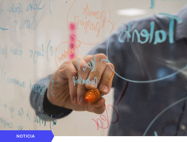 Portada de noticia que muestra un primer plano de una mano escribiendo conceptos de talento y estrategia sobre una pizarra de cristal, con etiqueta azul de NOTICIA en la esquina inferior.